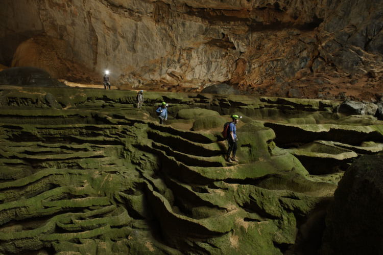 Hang Son Doong explorers navigate an algae-covered cavescape.